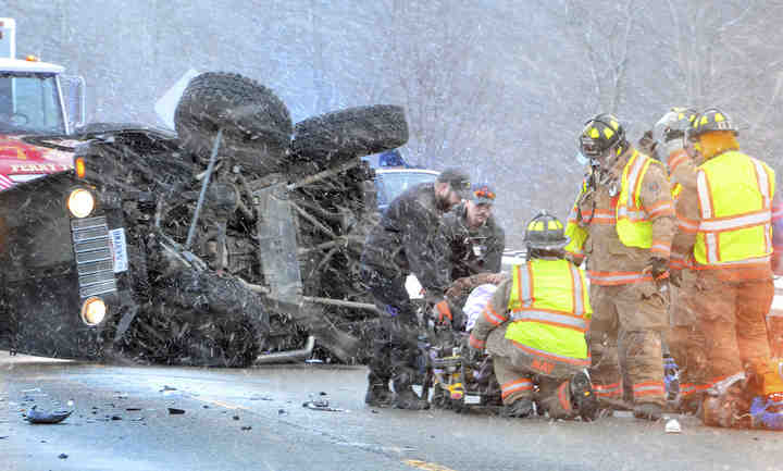 Haden Gostey, 23, of Lisbon is tended to by EMT ambulance personnel and Perry Township firefighters at the scene of a head-on collision on the US Route 62 bypass.     (Patricia Schaeffer / The (Lisbon) Morning Journal)
